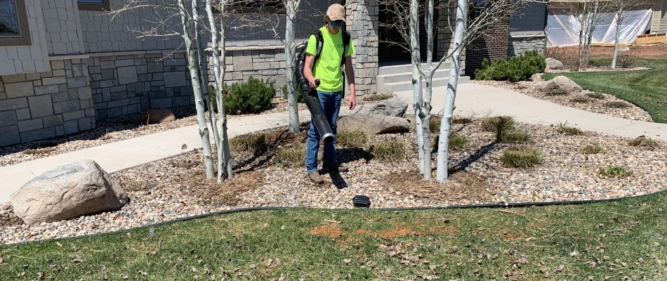 Yard Barbers professional leaf blowing away debris in a yard in Sioux Falls, SD.